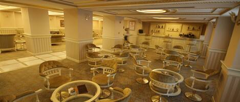 Un vestíbulo de hotel con varias zonas de estar, una recepción y un bar.