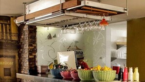 Zona de bar con pared de piedra, taburetes y mostrador con cestas de aperitivos y botellas.