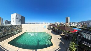Zona de piscina en la azotea con vistas despejadas al horizonte de la ciudad, un letrero con la inscripción 'Hotel Buena Vista Express' y mobiliario para estar al aire libre.