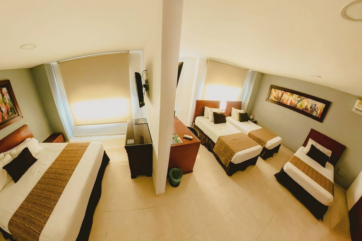 Habitación de hotel con dos camas, un escritorio y un ventanal grande.