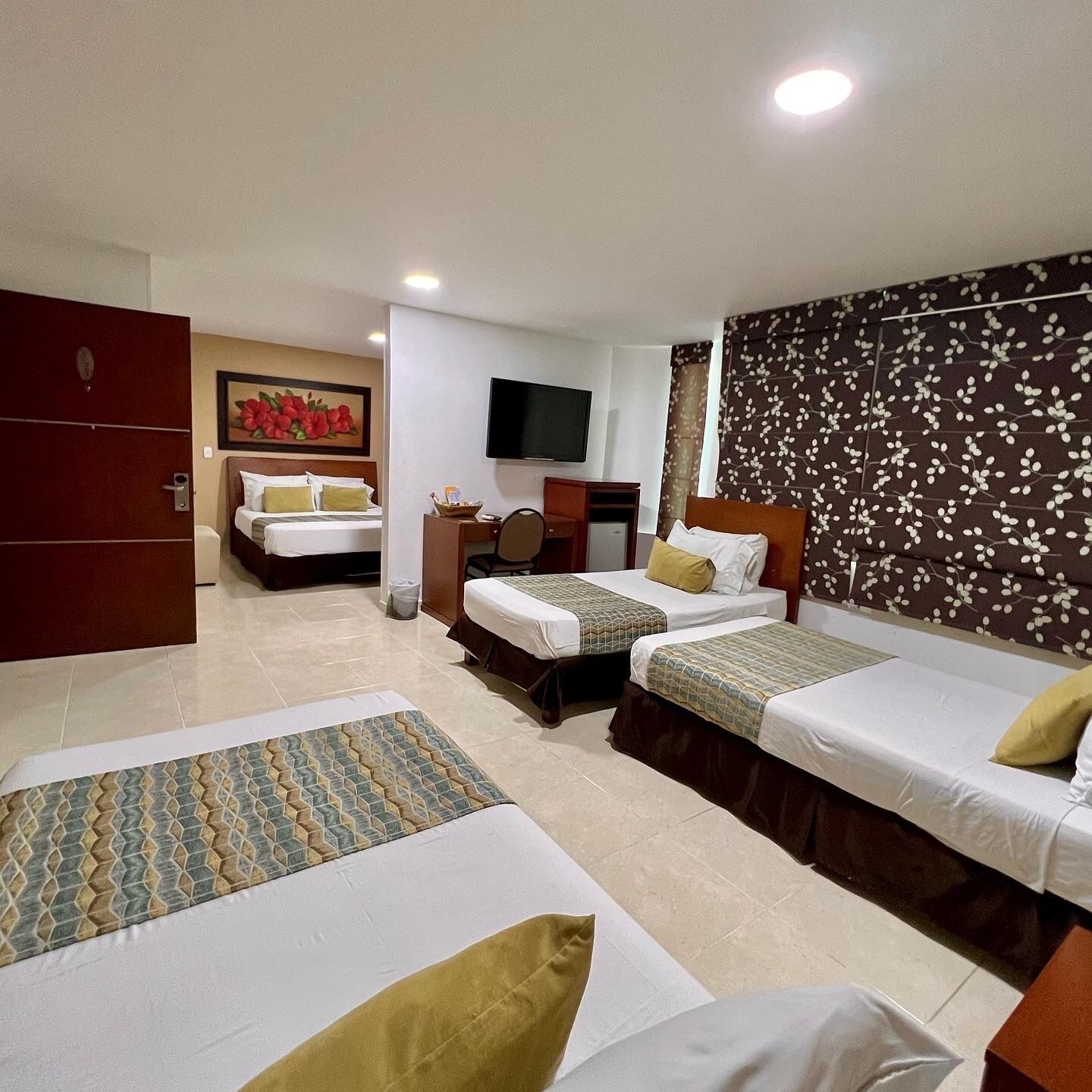 A hotel room with two single beds, a desk with a chair, a TV, and a wardrobe.