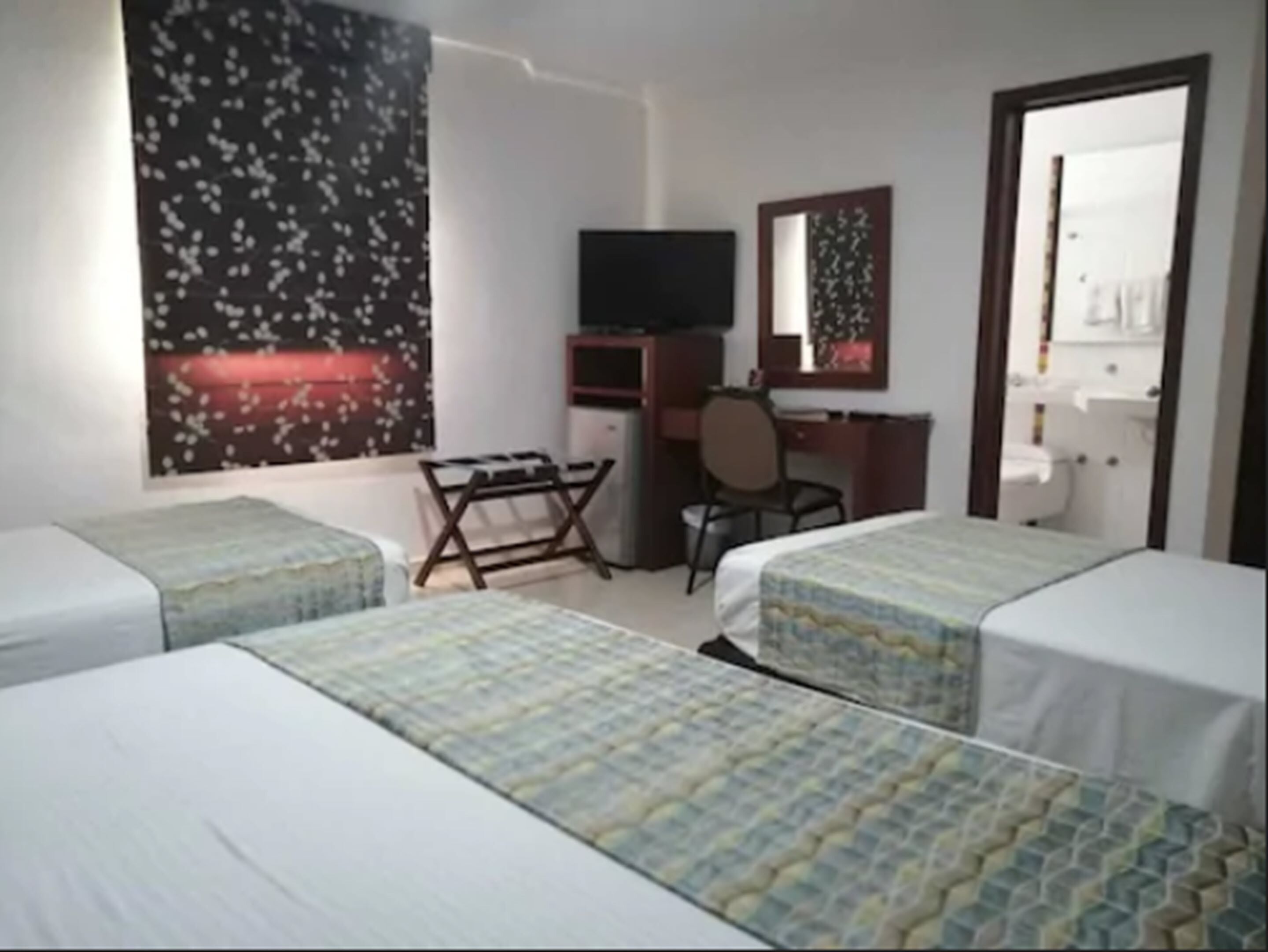 Una camera d'albergo con due letti, una scrivania, una sedia, una televisione e uno specchio.