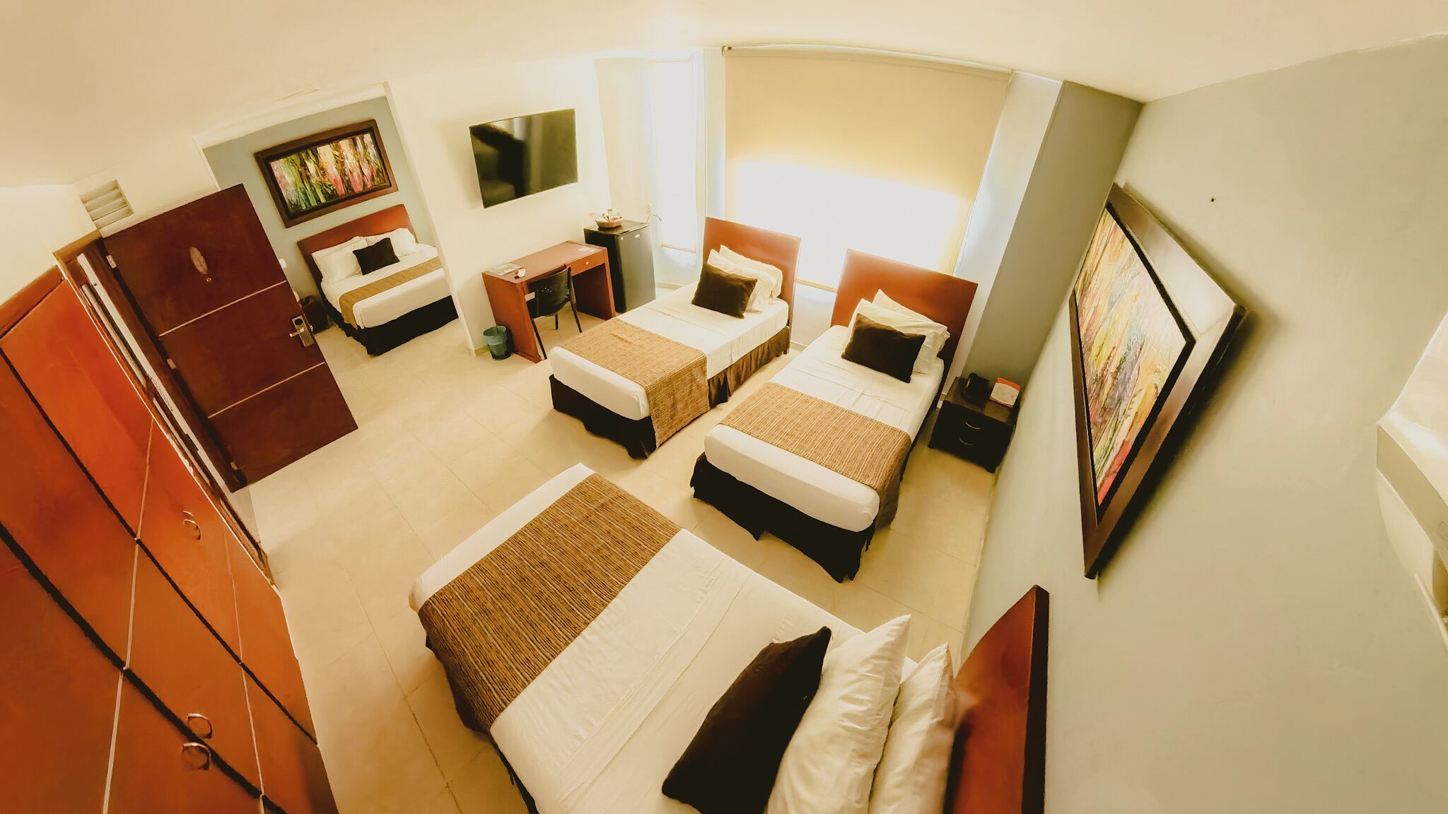 Une chambre d’hôtel avec deux lits, un bureau, une chaise, une télévision et une armoire.