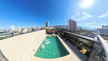 Piscina no terraço com vista para a cidade, rodeada por edifícios e céu limpo.