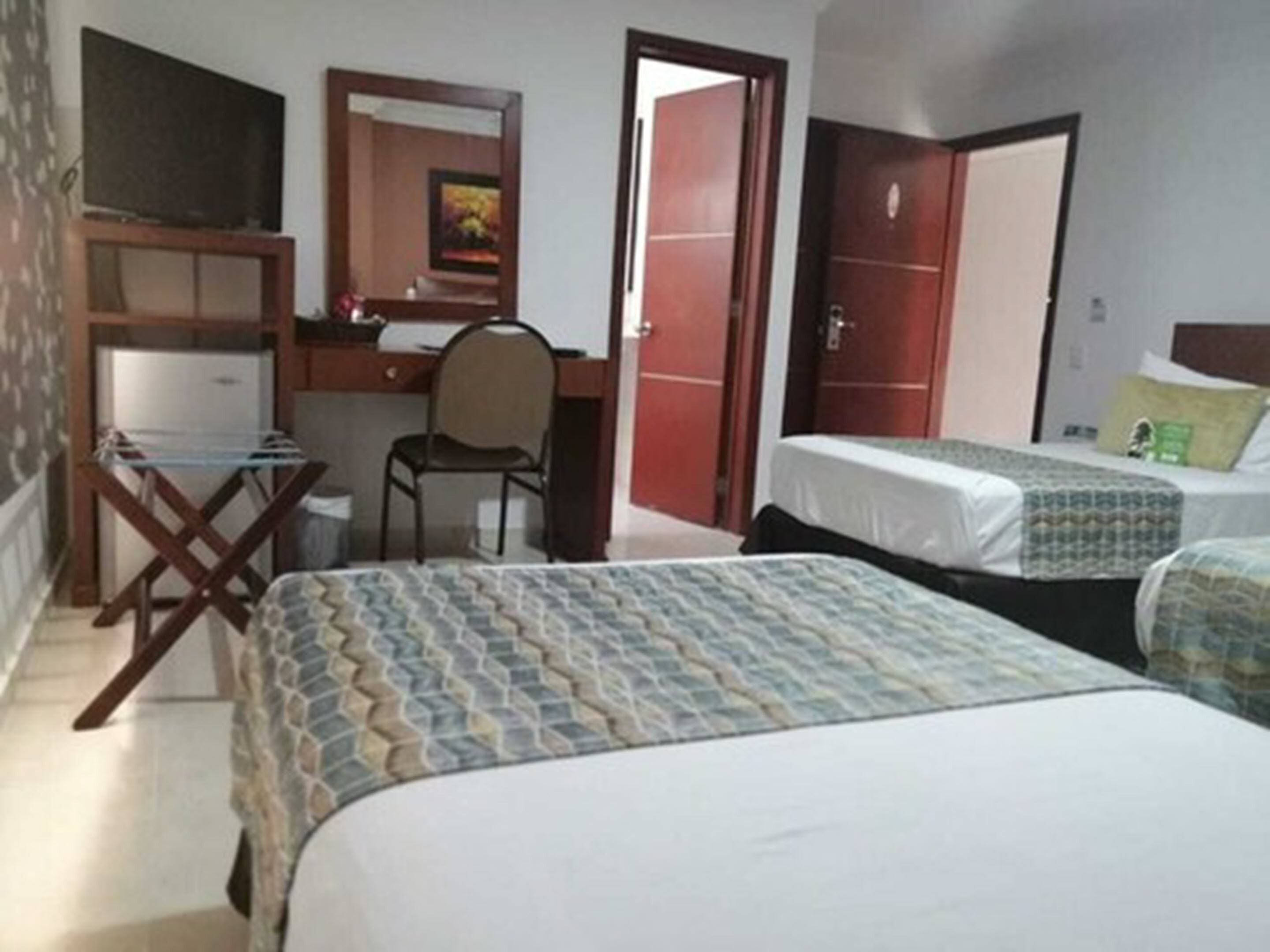 A hotel room with a desk, chair, two beds, and a wardrobe.
