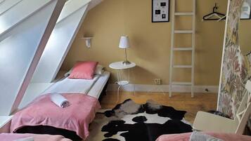 A bedroom with two beds, a small round table, a ladder, and a cowhide rug.