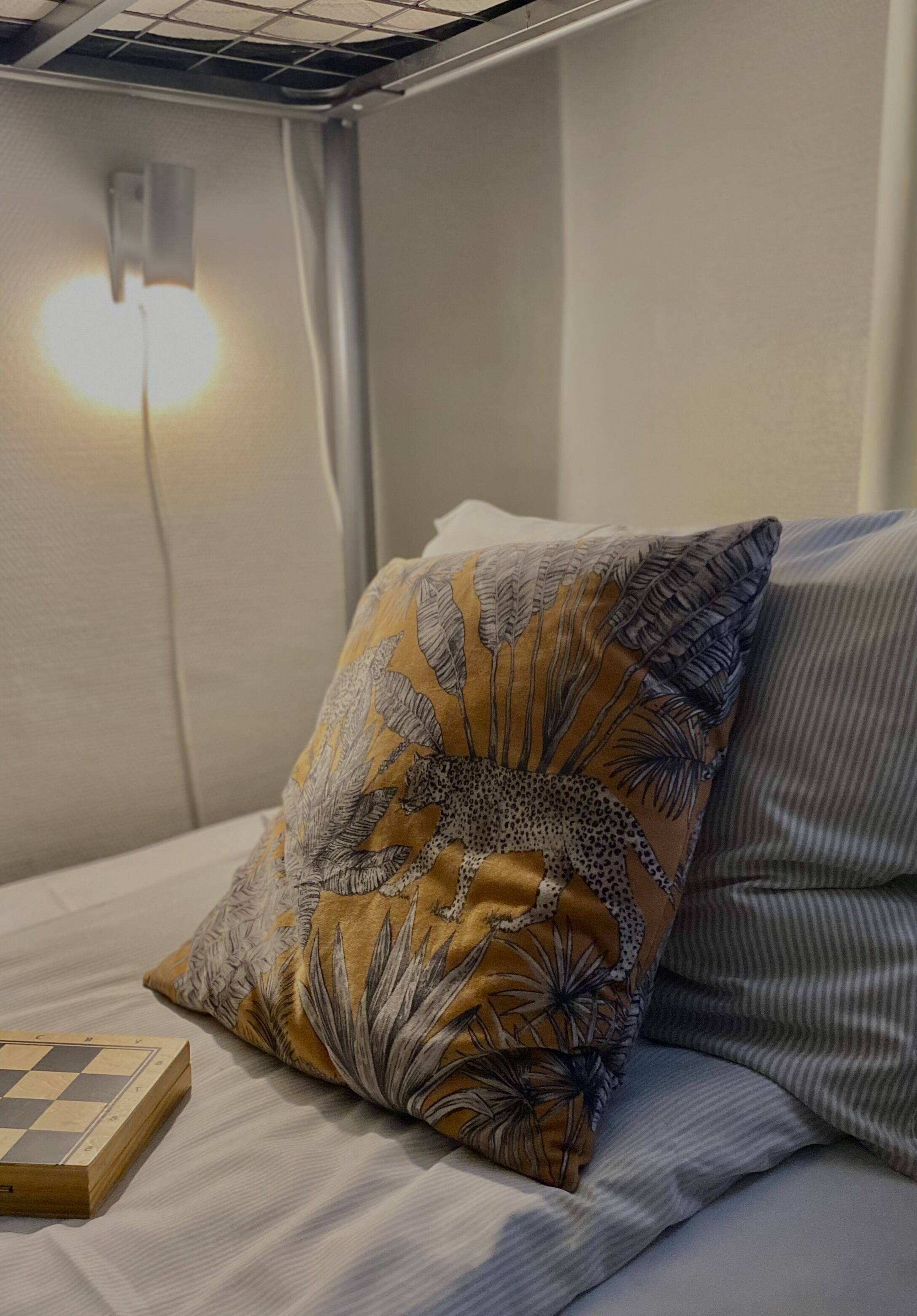A bed with a patterned pillow and a wooden chessboard.