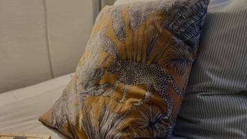 Una cama con un cojín estampado y un tablero de ajedrez de madera.