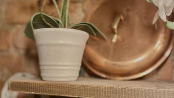 Een witte orchidee in een pot op een plank met een koperen kom en een kleine metalen lepel.