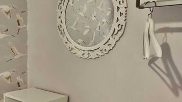 A wall with a decorative mirror and a white shelf unit.