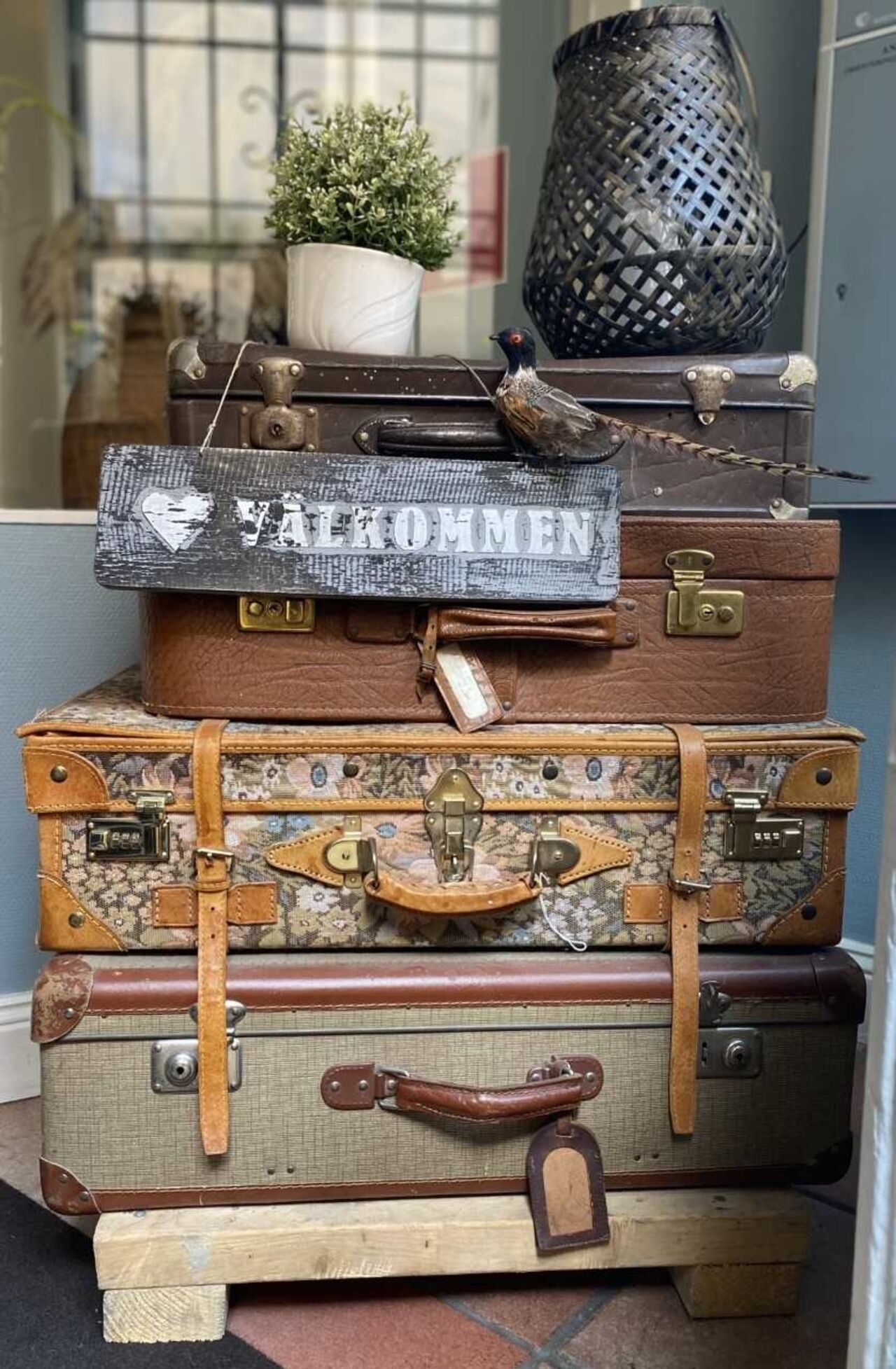 A stack of vintage suitcases with a sign that reads "WELCOME".