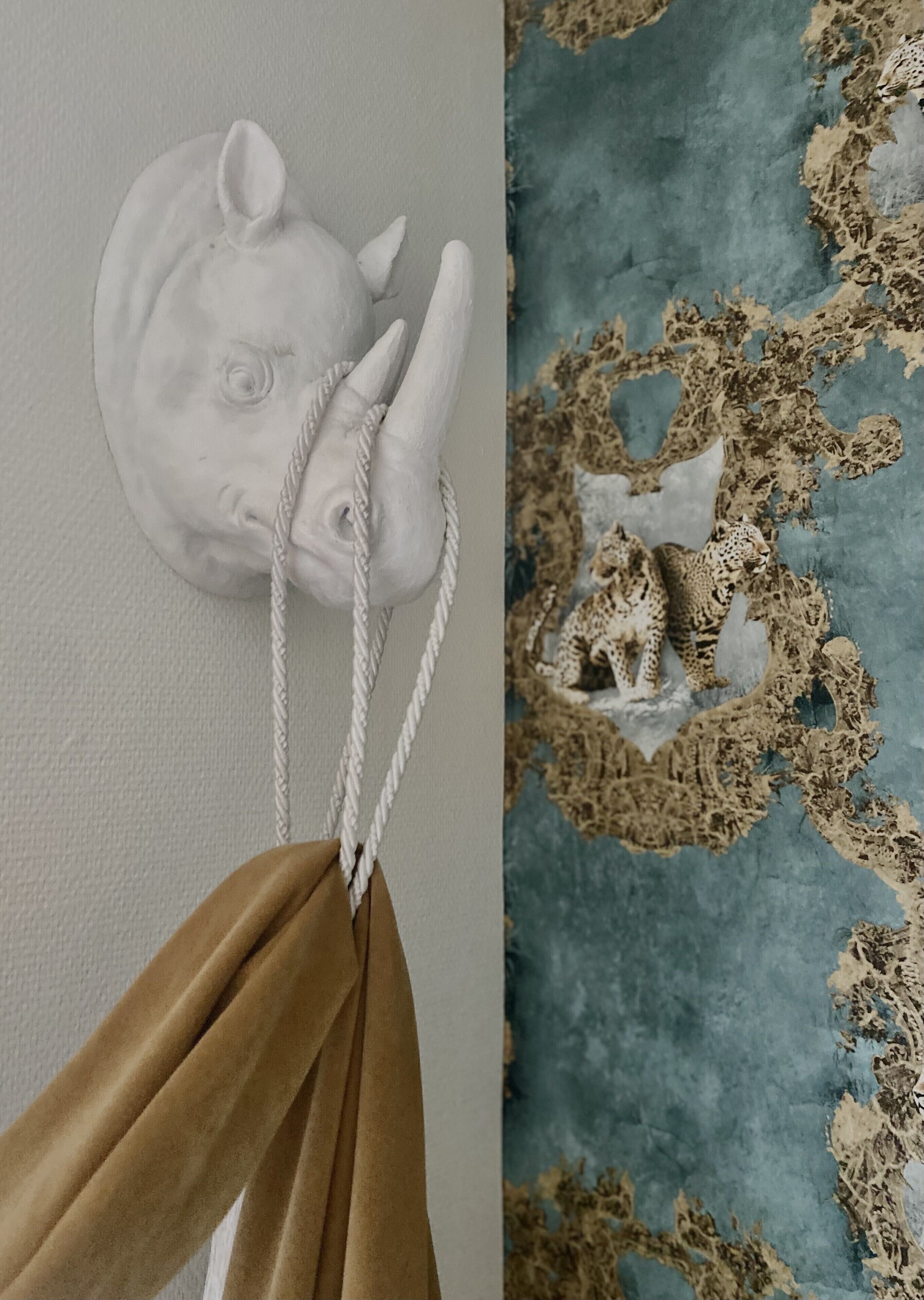 Escultura en la pared de la cabeza de un rinoceronte con una cuerda atada al cuello.