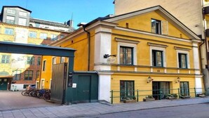 A yellow building with a green door and windows, number 44, with a bike rack outside. - Lilla Brunn - Hostel (Stockholm)