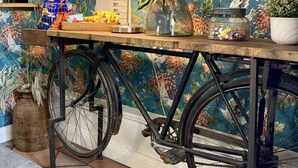 A room with a bicycle as a table, a lamp, and a floral wallpaper. - Lilla Brunn - Hostel (Stockholm)