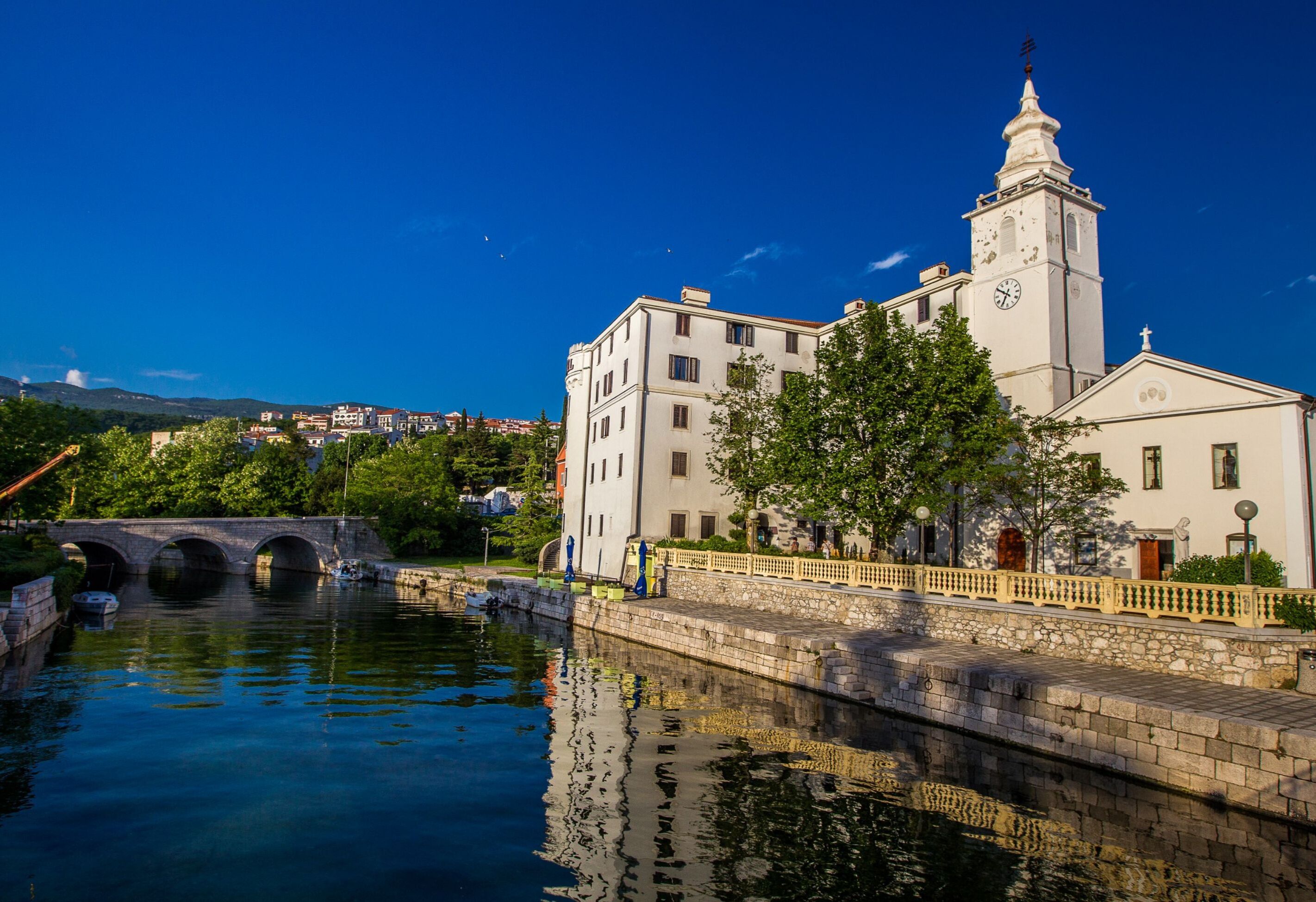 A historic building with a clock tower, a bridge, and a canal.