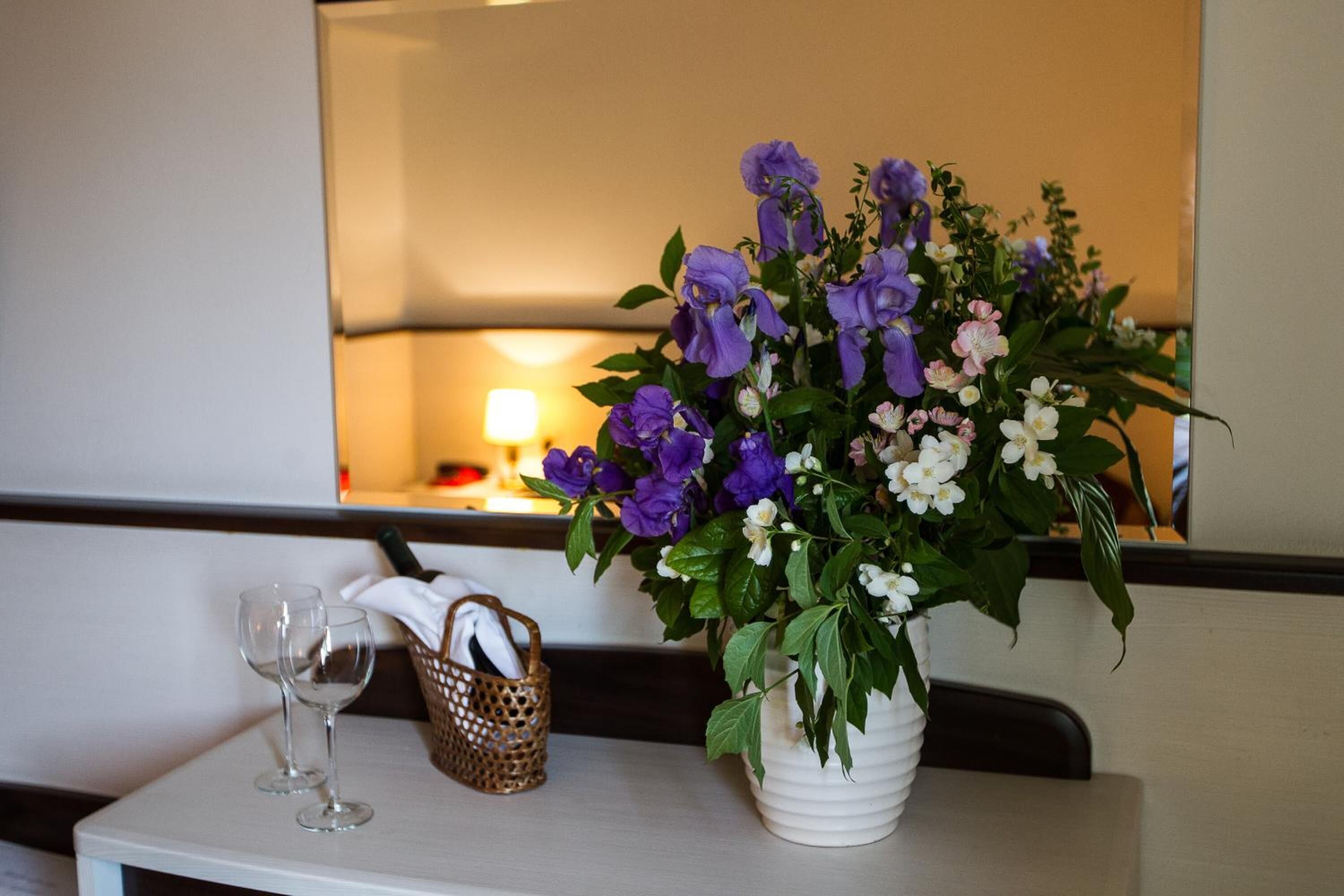 A table with a vase of flowers and two empty wine glasses.