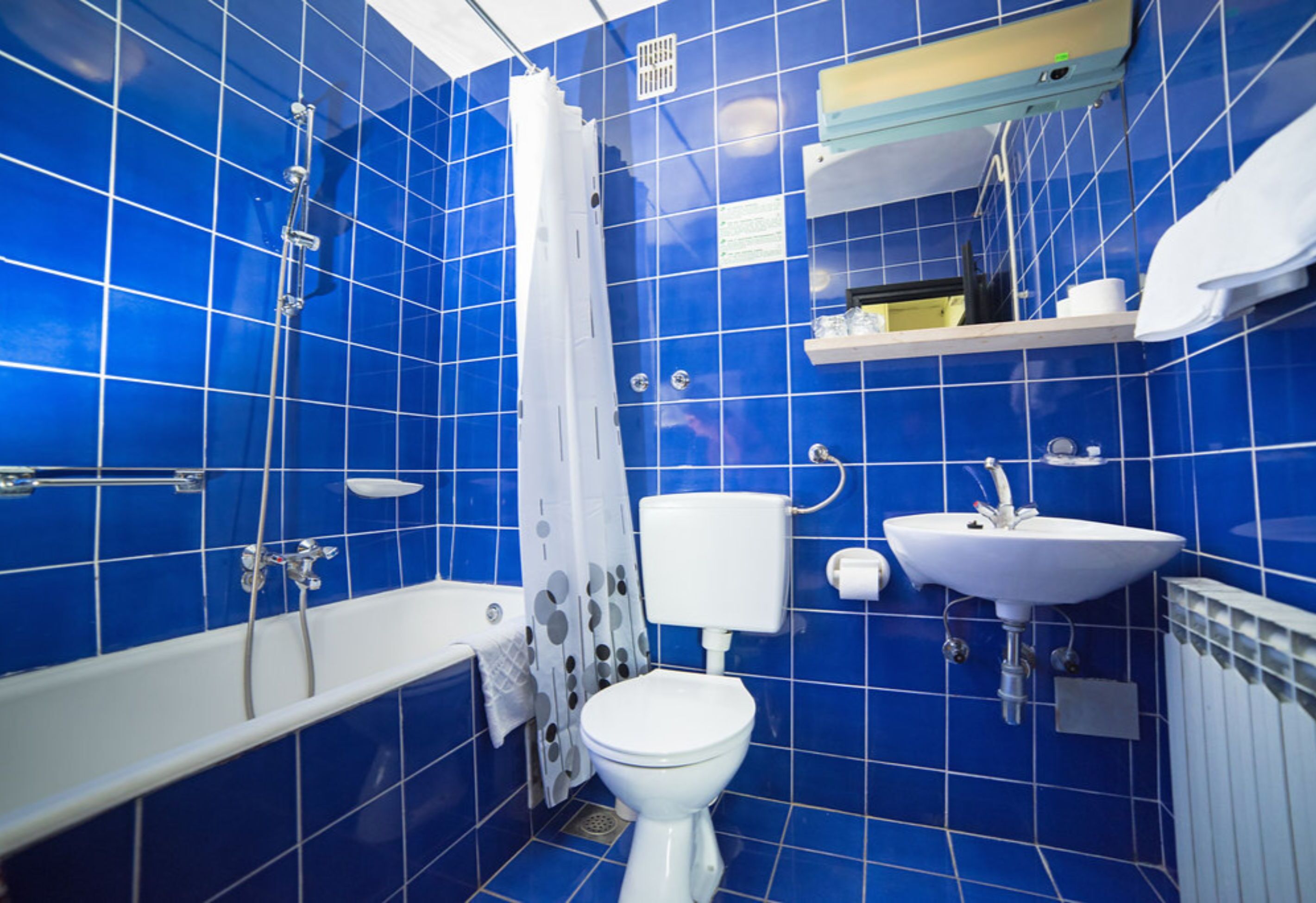 A bathroom with blue tiles, a white bathtub, a toilet, and a sink.