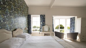 A bedroom with a large bed, a desk, two chairs, and a wardrobe.