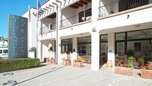 A hotel with a prominent sign, outdoor seating, and potted plants. - Michelangelo Holiday & Family Resort (Comacchio)