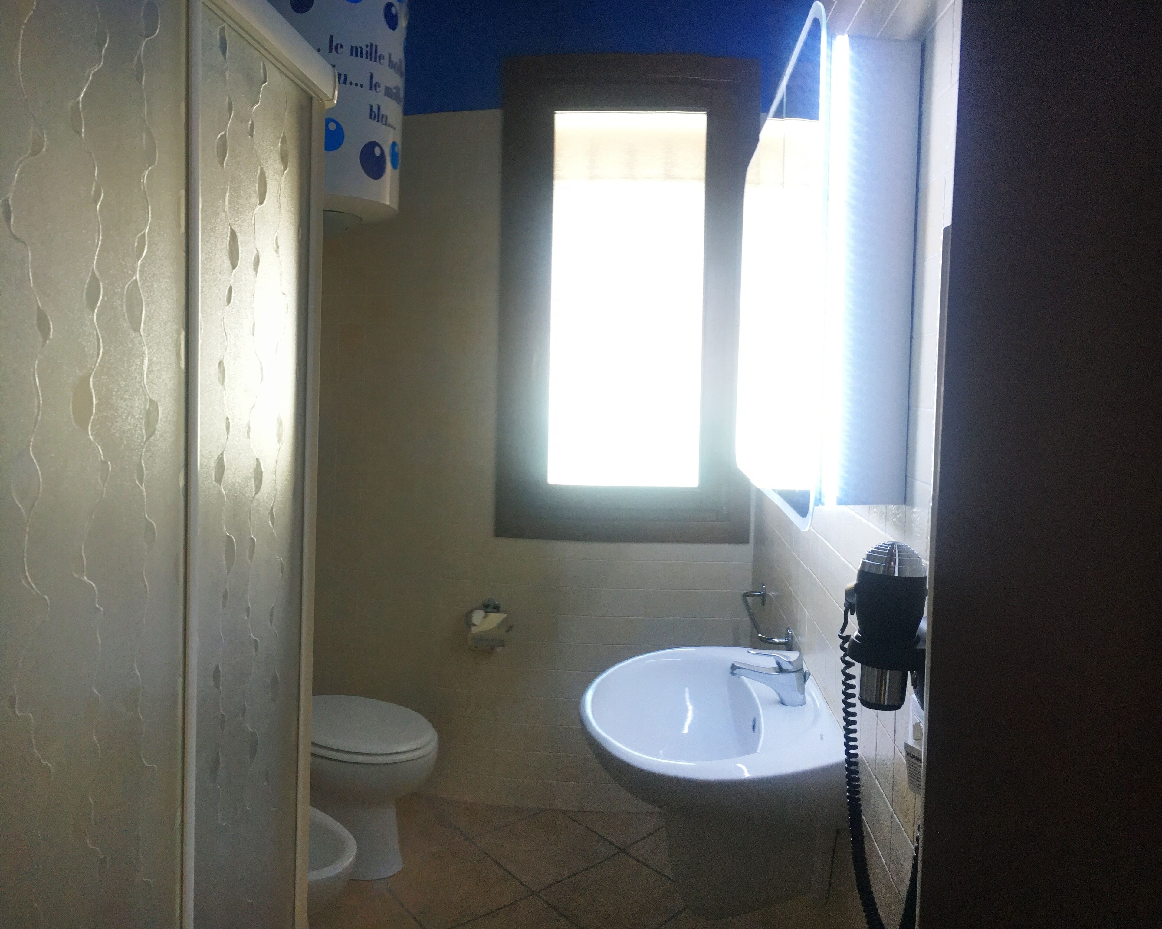 A bathroom with a toilet, sink, and a window.
