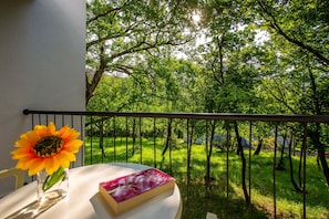 Enjoy a serene view of the lush garden from this balcony, featuring a single sunflower and a book.