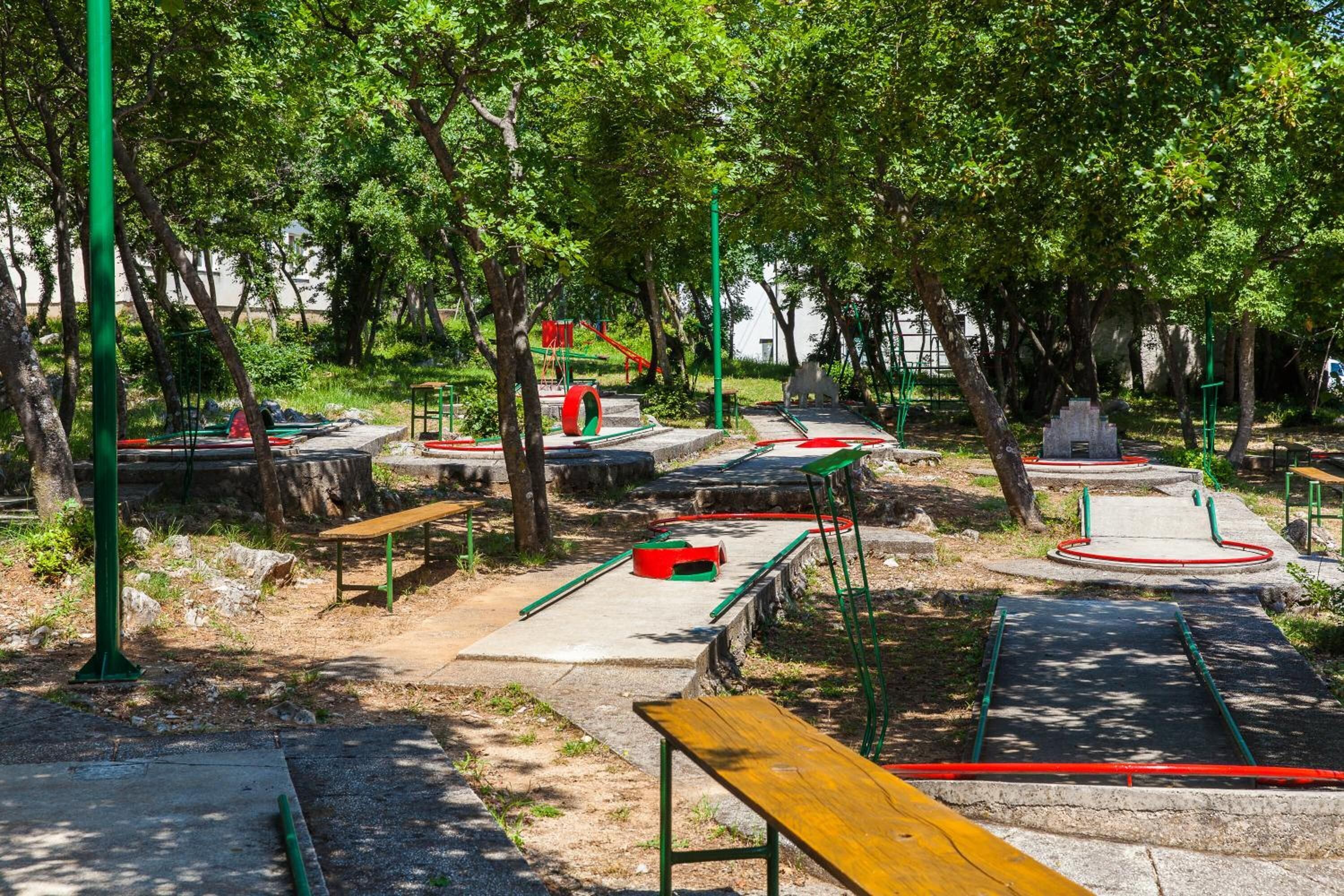 A park with playground equipment, benches, and trees.