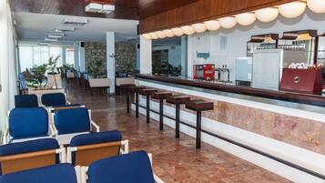 A hotel lobby with a reception desk, seating area, and a stone wall.