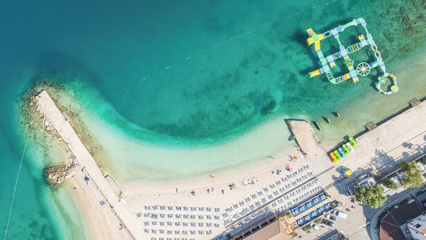 An aerial view of a beach with a parking lot and a building. - Hotel Slaven (Crikvenica)