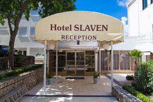 La entrada al Hotel Slaven, con una zona de recepci ón, una pared de piedra y plantas en macetas.