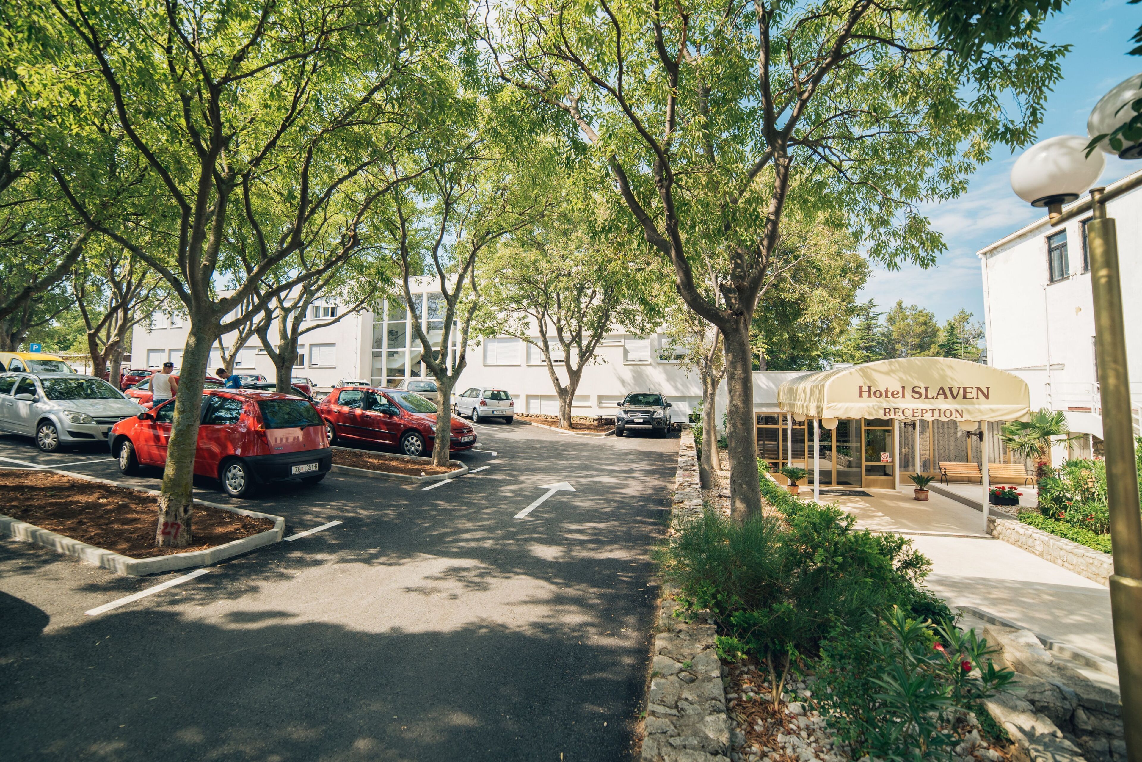 A hotel reception with a clear driveway and parked cars.