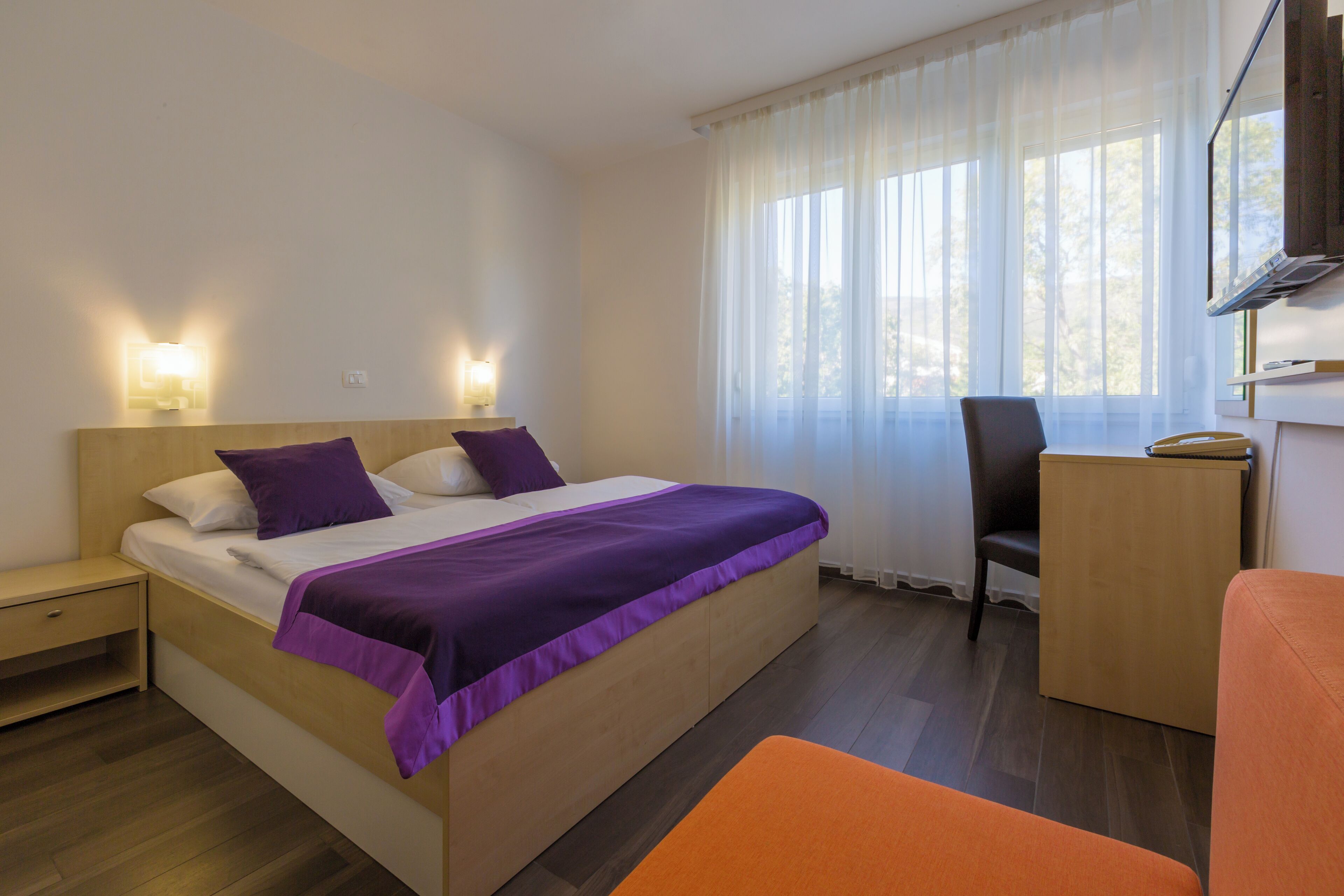 Un dormitorio con cama, mesitas de noche, una silla y un escritorio.