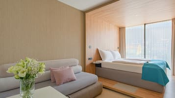 Una habitación de hotel moderna con sofá, cama y un florero con flores.