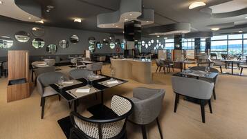A modern restaurant with round mirrors on the walls, a central bar, and tables with chairs.