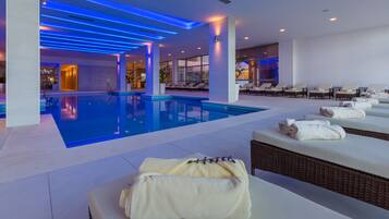 Uma área interna de piscina moderna com espreguiçadeiras e toalhas.