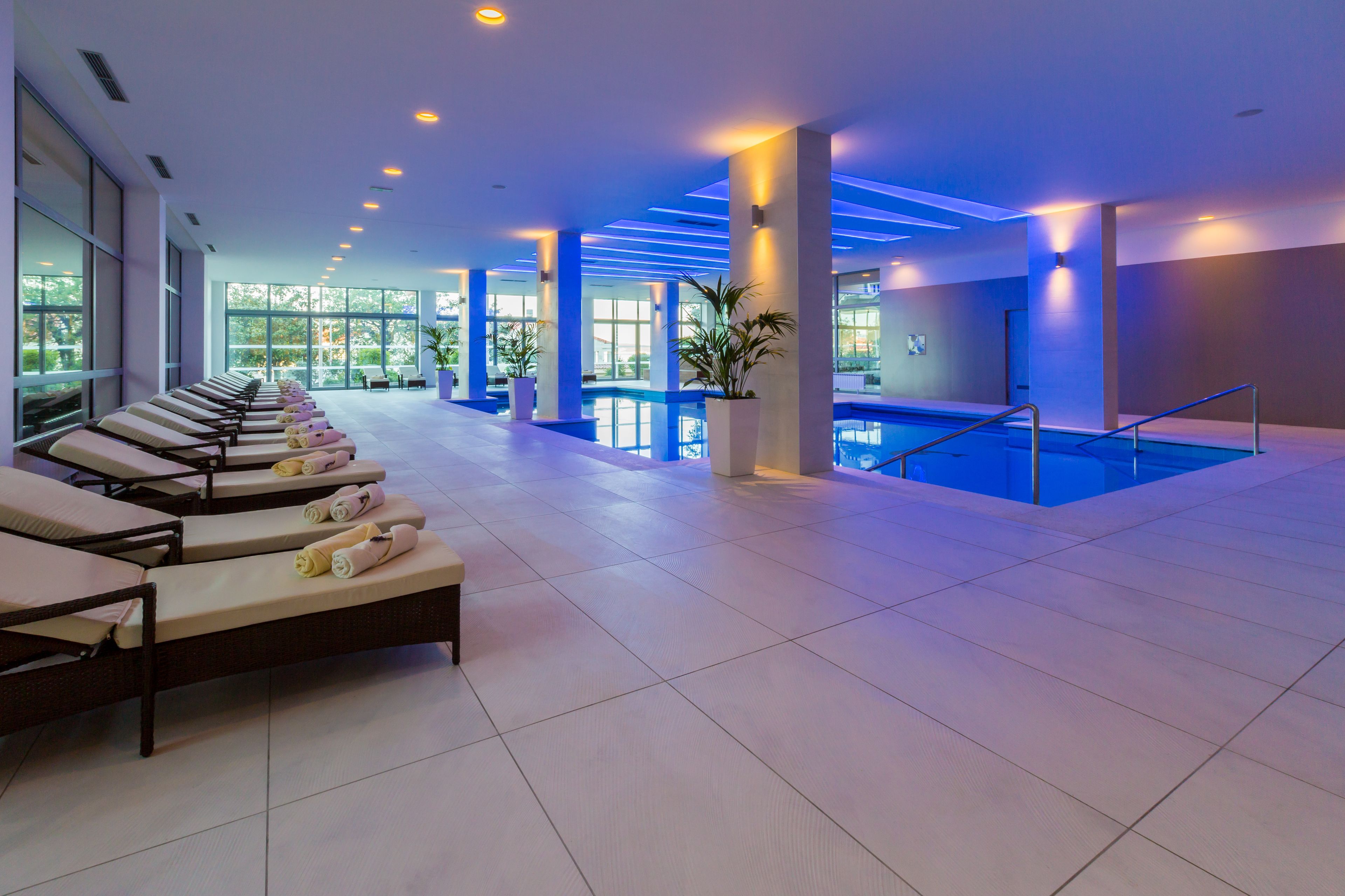 Un área de piscina interior moderna con sillones de descanso y un amplio ventanal.