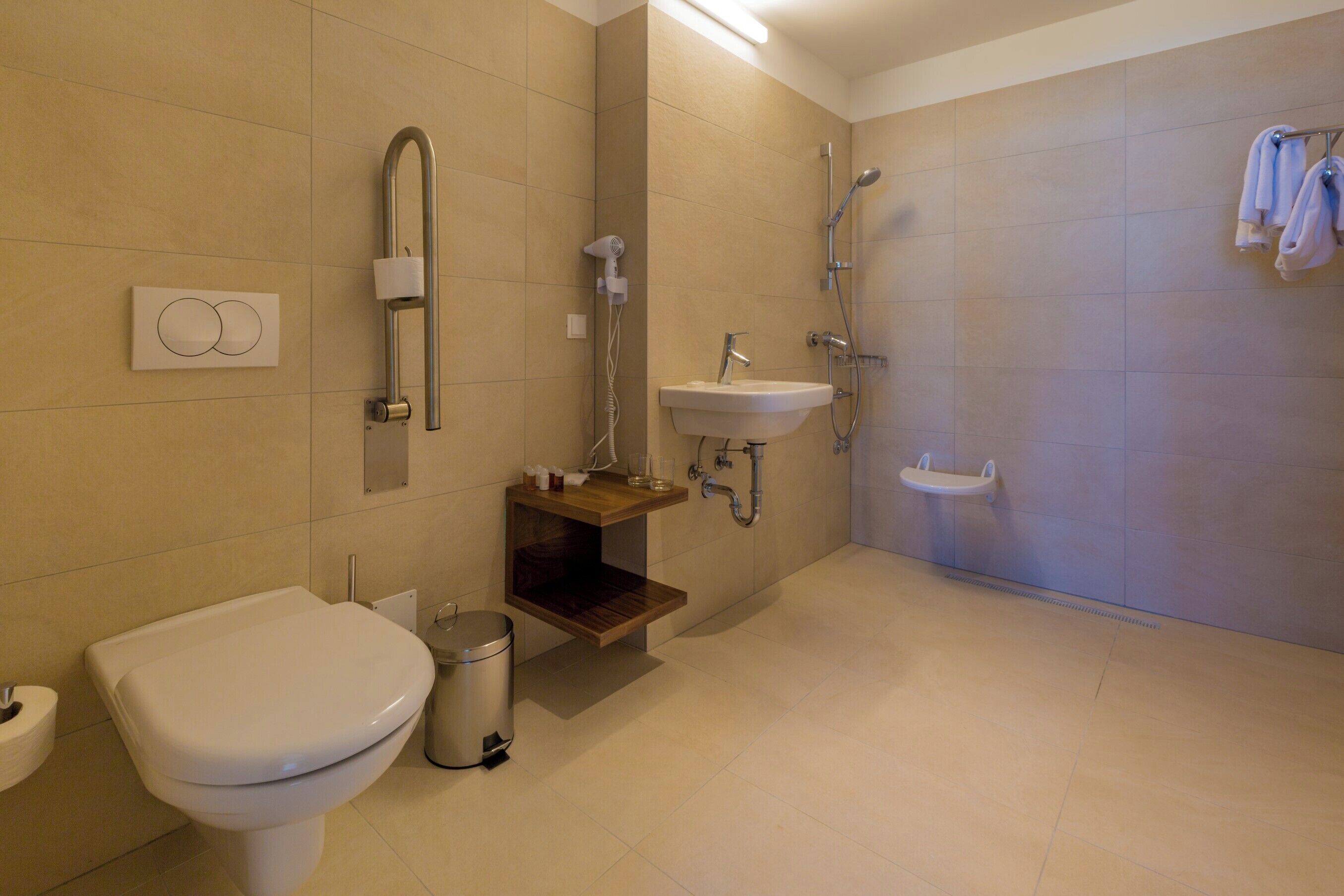 Ein modernes Badezimmer mit Toilette, Waschbecken, Dusche und Handtuchhalter.