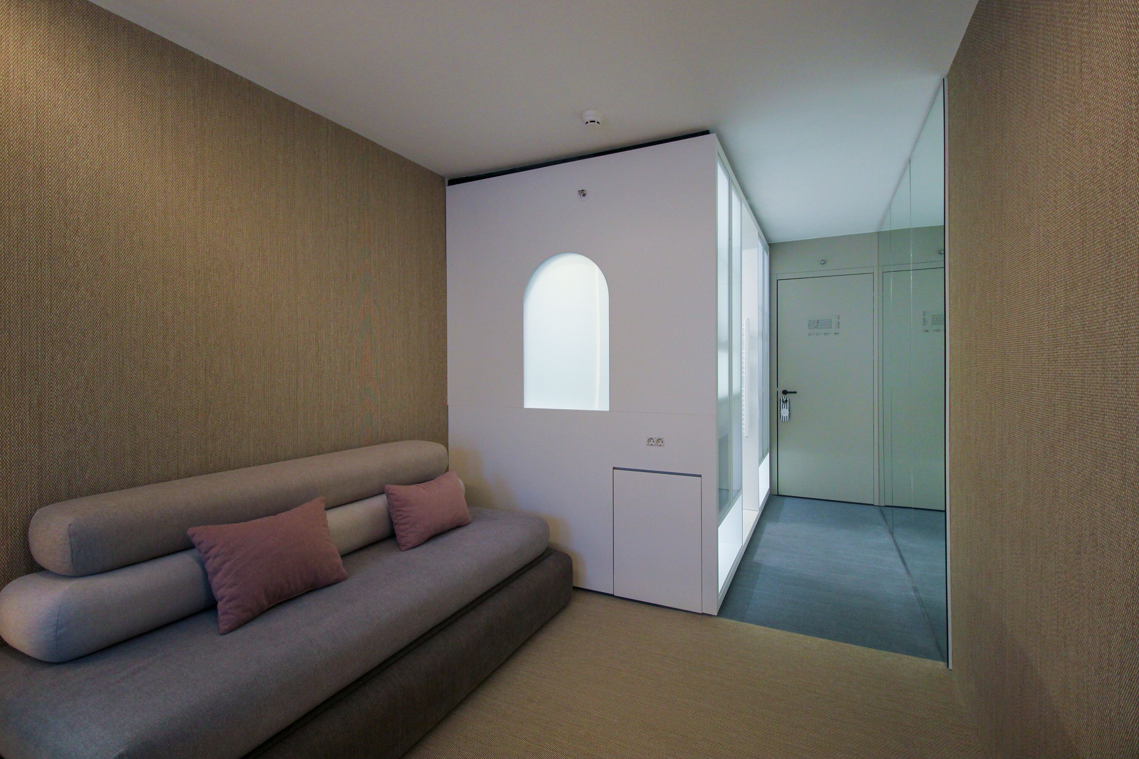 Una habitación moderna con sofá, una puerta con ventanal y un separador de vidrio.