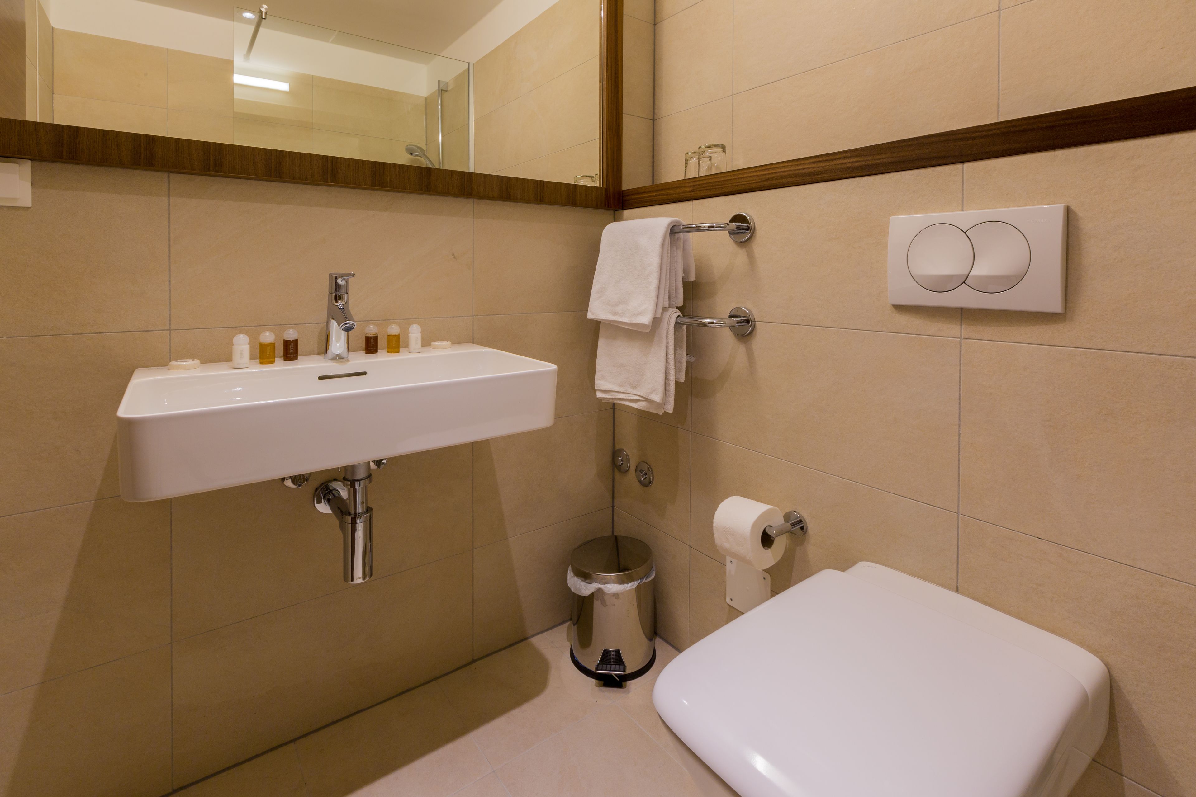 A bathroom with a white sink, mirror, and toilet.