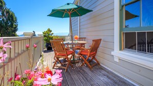 A wooden deck with a table and chairs, a green umbrella, and a flower arrangement. - Fairholme Manor (Victoria)