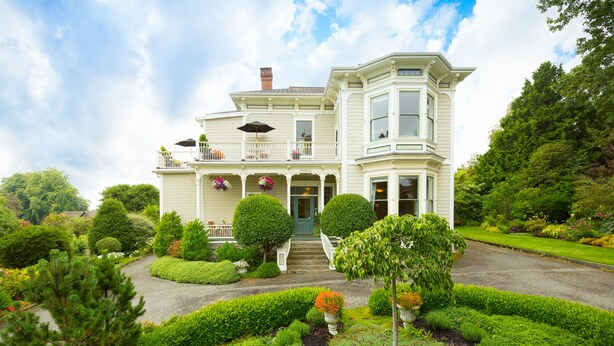 A large, two-story house with a front porch, multiple windows, and a well-maintained garden. - Fairholme Manor (Victoria)