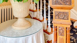 A staircase with a white railing, a white vase with green leaves, and a wooden decorative piece. - Fairholme Manor (Victoria)