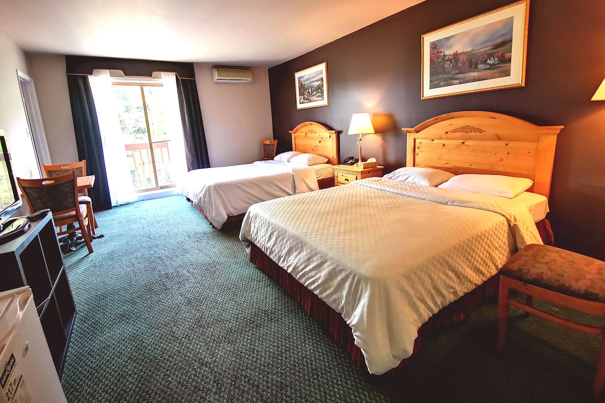 A hotel room with two beds, a desk, a chair, a lamp, and a painting on the wall.