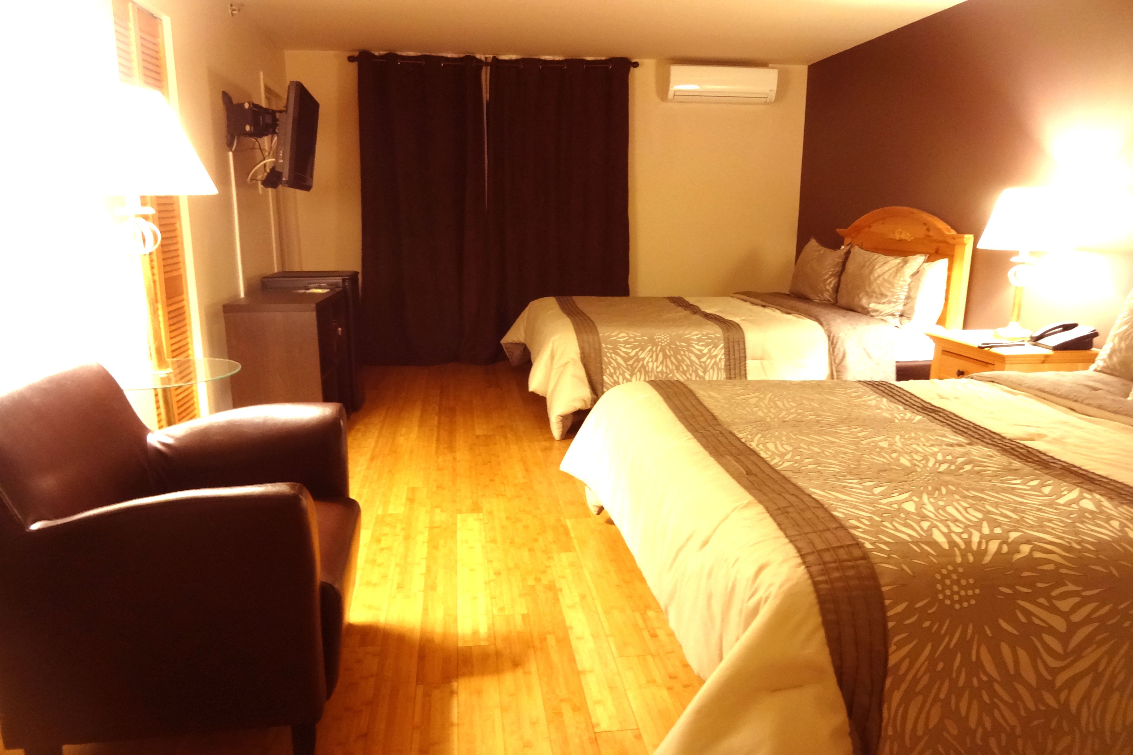 Ein Hotelzimmer mit zwei Betten, einem Schreibtisch, einem Stuhl und einem Fernseher.