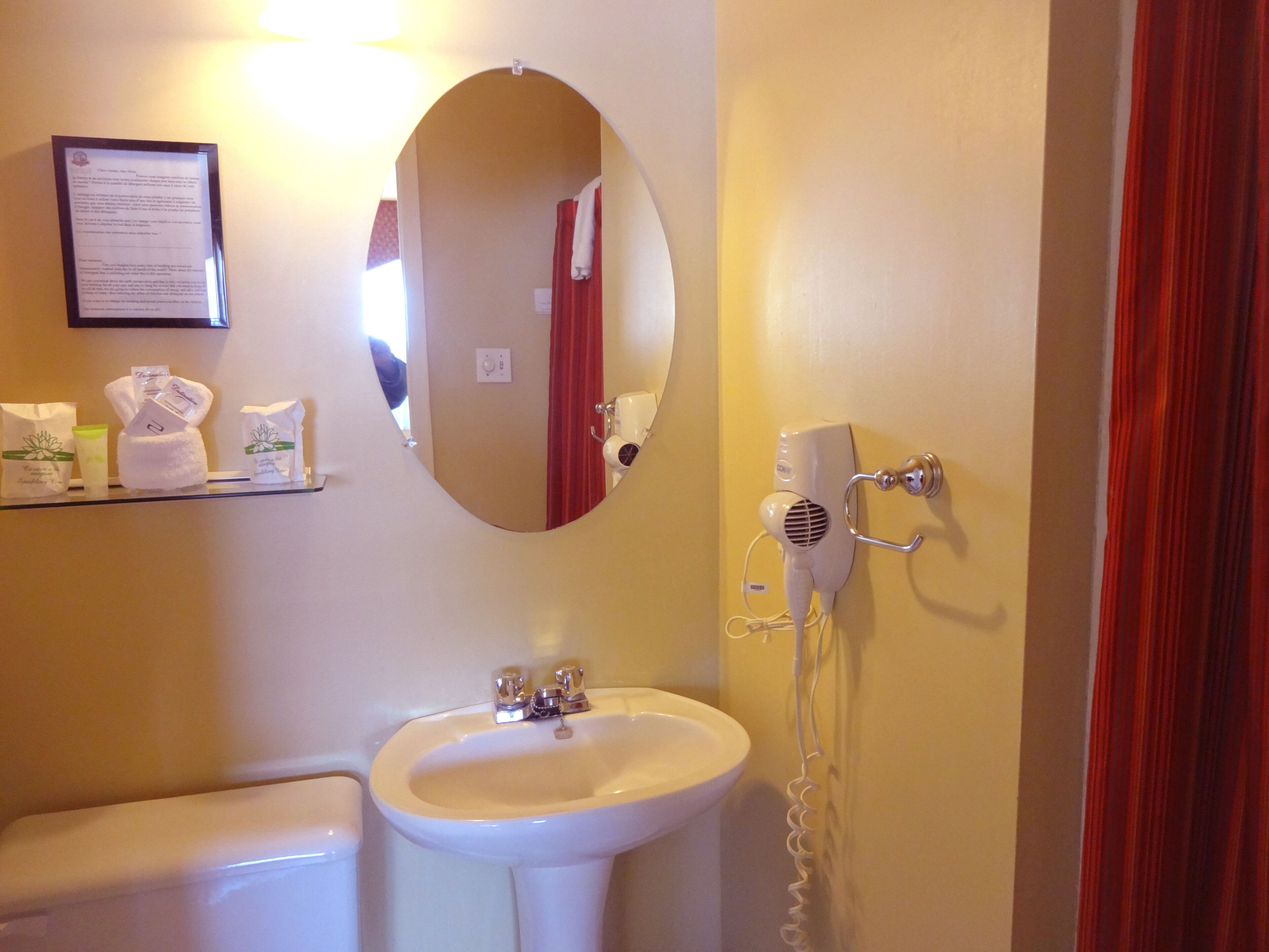 Een badkamer met een wastafel, spiegel en een föhn aan de muur.