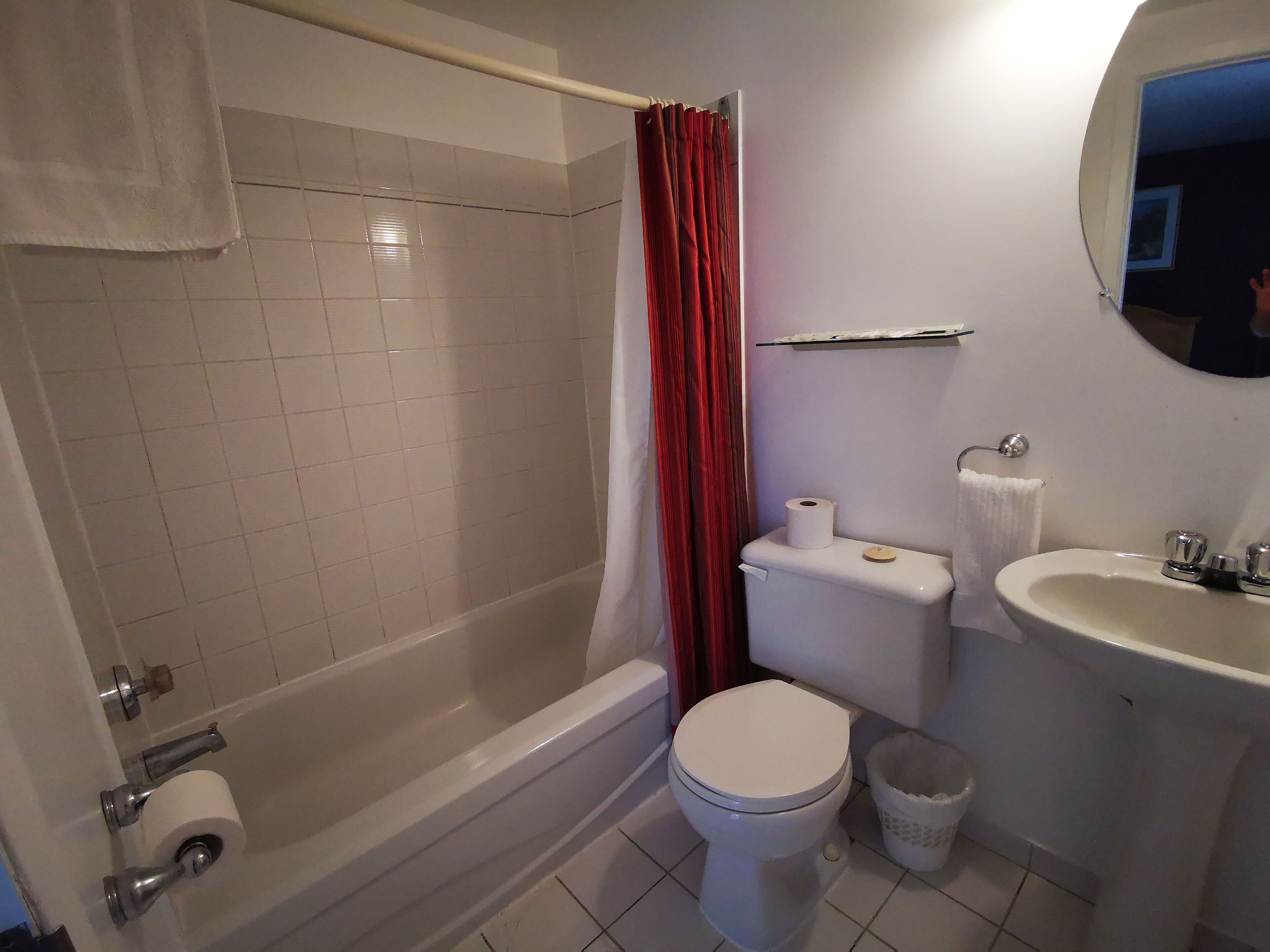A bathroom with a bathtub, toilet, sink, and a mirror.