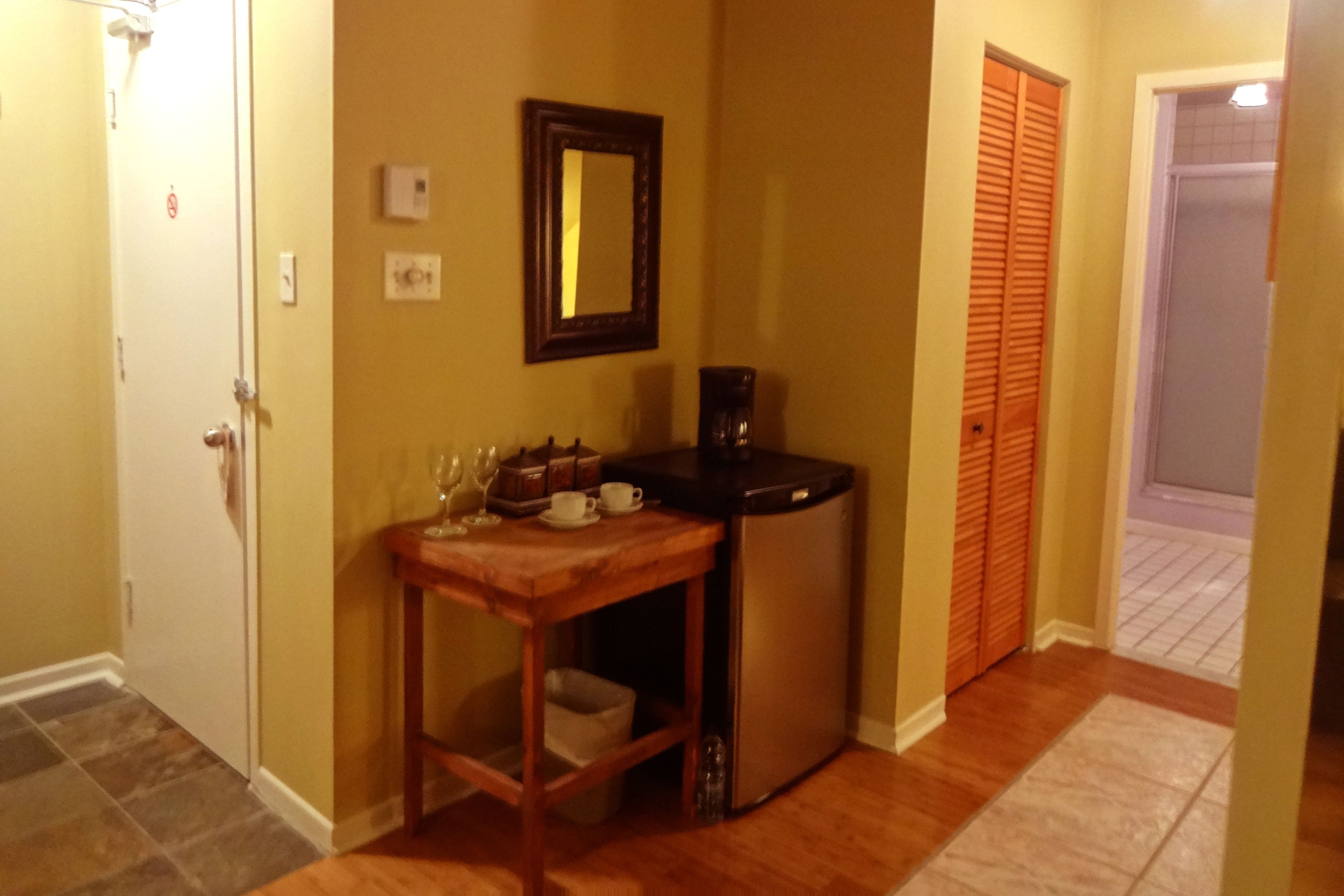 Una cocina compacta con una mesa de madera, un refrigerador y un espejo en la pared.