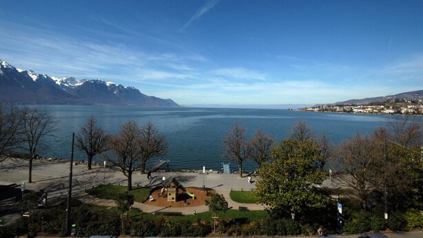 A lakeside park with playgrounds and benches, surrounded by trees and mountains in the background. - Hotel Parc & Lac (Montreux)