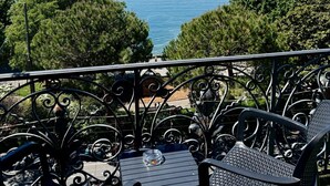 A balcony with metal railings, a table, and two chairs overlooking a lake with a distant shoreline. - Hotel Parc & Lac (Montreux)