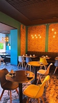 Un restaurante con mesas redondas, sillas e iluminación colgante.