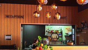 A reception area with a wooden wall, a reception desk, a bar area, and a plant centerpiece. - Hotel Parc & Lac (Montreux)